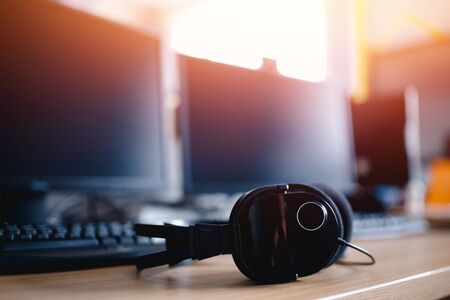 Close-up of headphones. In background computer, monitors for sound recording and games. Sunlightの写真素材