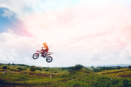 Racer on motorcycle dirtbike motocross cross-country in flight, jumps and takes off on springboard against sky. Concept active extreme rest motocross.の写真素材