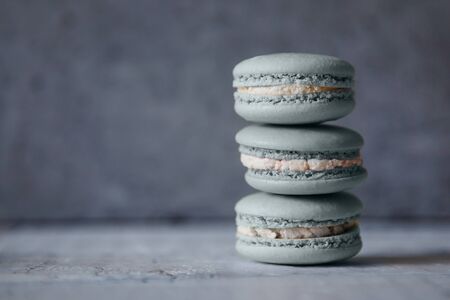 Macaroon. Macaron on gray neutral loft background, stand on plate of different colors. Wooden background.の写真素材