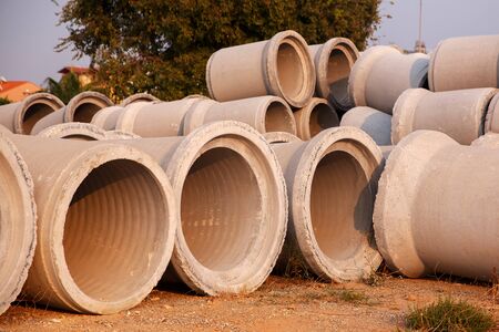 Rings of concrete pipe stand on warehouse site and are waiting for installationの写真素材