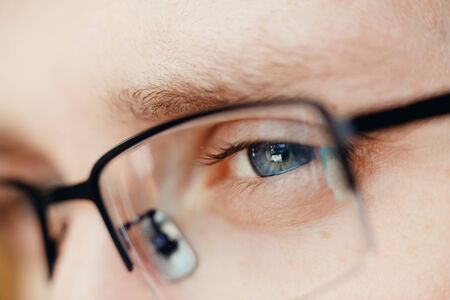Close-up of glasses and blue eye of man. Concept businessman, student, read, reflect, think.の写真素材