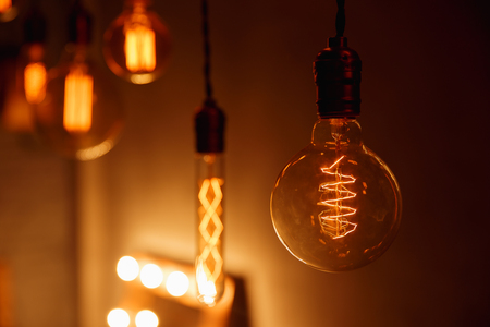 Retro Edison light bulb with unusual spiral. Edison lamp on black background. Incandescent lightbulb with dark background with bokeh.の写真素材