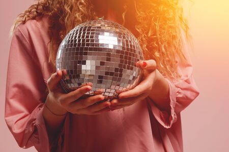 Close-up of disco ball, girl in pink dress is holding ball for parties and dances. Concept holiday, birthdayの写真素材