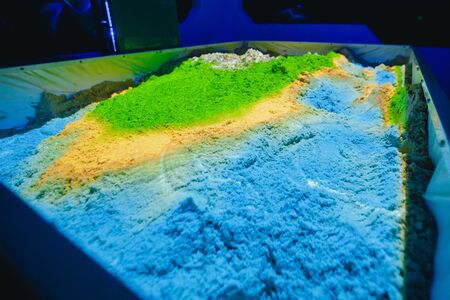 Kinetic sand. Tray with sand, reproduction of surface of earth, is controlled by smart projectorの写真素材