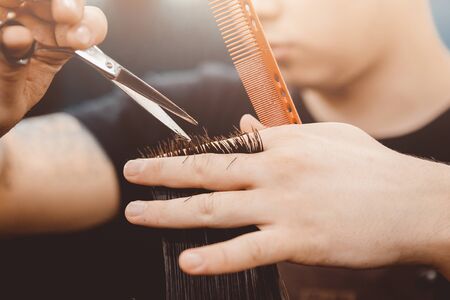 Barber master hairdresser does hairstyle and style with scissors and comb. Concept Barbershop.の写真素材