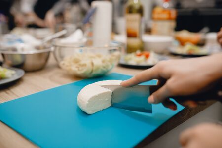 Close-up of a girl cuts a sharp cheese knife.の写真素材