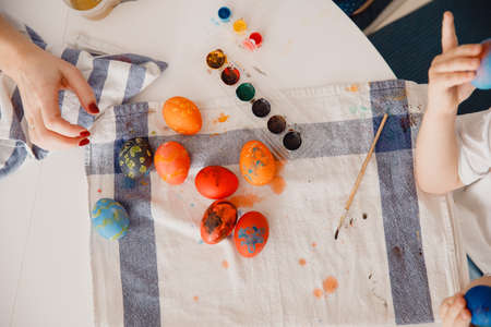 Mother, daughter and son paint eggs. White kitchen. A happy family is preparing for Easter. Top viewの写真素材