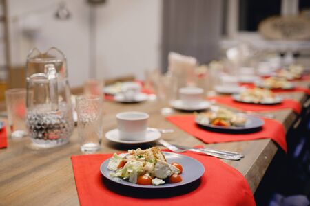 Wooden table with separated plates with salad, tea mugs and glass glasses. Concept dinner, tea party.の写真素材