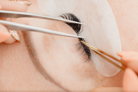 Eyelash extension procedure. Beautiful woman with long eyelashes in beauty spa salon.の写真素材