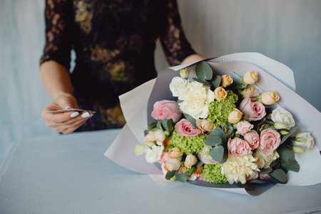 Florist work keeps card for payment. Woman making fashion modern bouquet rose of different flowersの写真素材