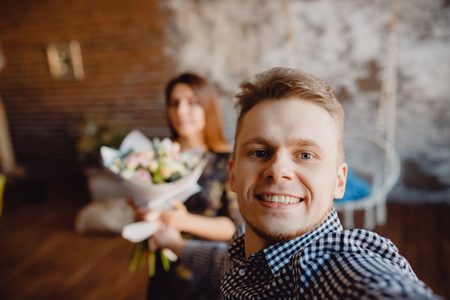 Selfie man gives a gift bouquet of flowers to a young woman. coupleの写真素材