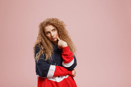 Young beautiful girl with curly hair doubts the choice of solution. Concept of choosing university,...