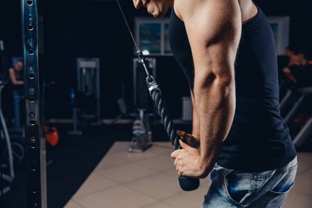 Close-up of man doing exercises on muscles of triceps in simulator. Muscles on arms, ligaments. Concept workout, bodybuilder in gym.の写真素材