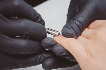 Manicure. Master applies varnish drawing on nails gel in manicure salon.の写真素材