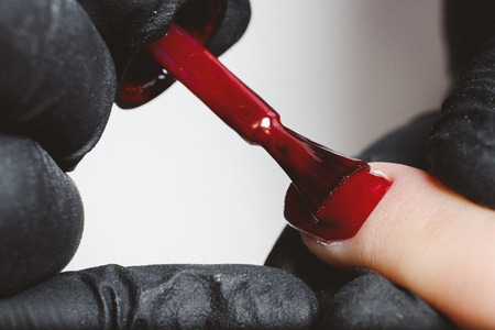 Manicure. Master applies varnish drawing on nails gel in manicure salon.の写真素材