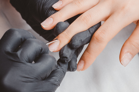 Manicure. Master applies varnish drawing on nails gel in manicure salon.の写真素材