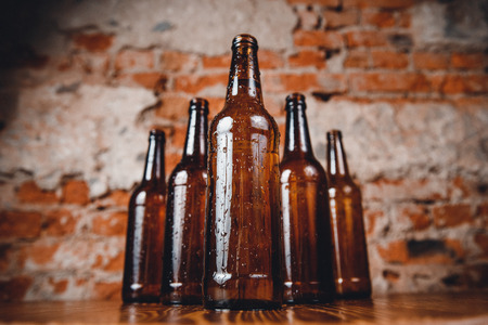 Row cold ice beer brown bottles glass with drops of water against brick wall. Concept craft breweryの写真素材