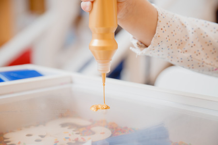 Child paints table with paint on transparent glass, concept development of kid motor skills of hands and art.の写真素材
