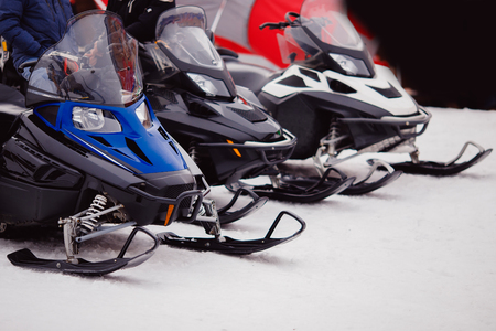 Number of snowmobiles of blue, black, white flowers stand on snow. Concept Walking through mountains.の写真素材