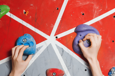 Close-up of artificial hooks and hands of climber on climbing wallの写真素材
