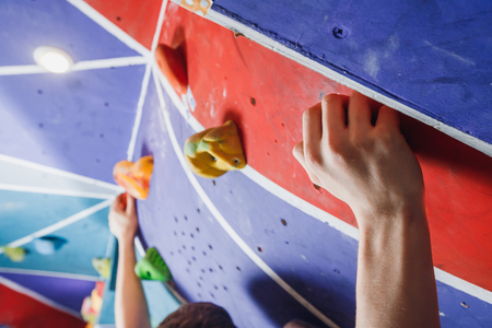 Climber clings to climbing wall with his hands.の写真素材