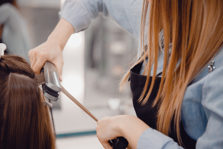 Close-up of master hairstylist ironing for straightening hair restores keratin and straightens hair.の写真素材