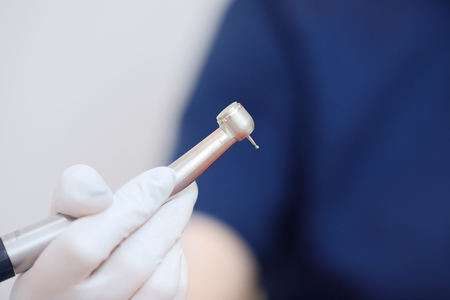 Close-up of drill for teeth in hands of dentist against background of patient woman.の写真素材