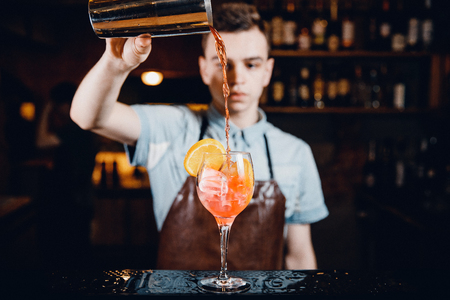 Close-up of barman mixes cocktail with ice orange, whiskey, liquor.の写真素材
