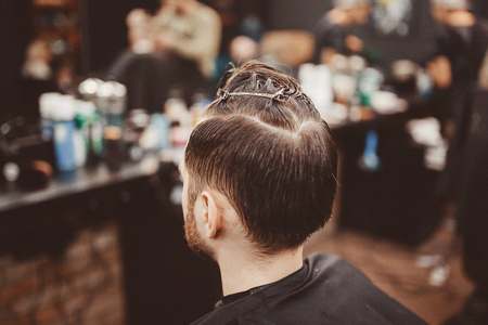 Barbershop. man in a hairdresser is preparing barber to cut hair with hairpin clips.の写真素材