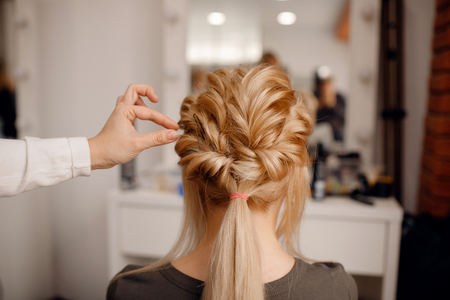 Close-up of woman hairdresser weaving plaits in beauty salon.の写真素材