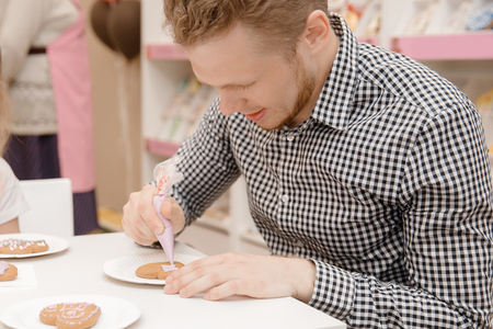 Decorating gingerbreads with colored glaze, man coloring cookiesの写真素材