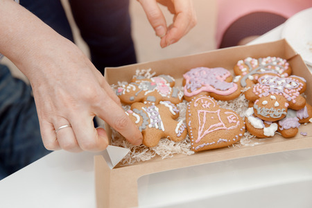 Decorating gingerbread cakes color glaze, girl showing cookiesの写真素材