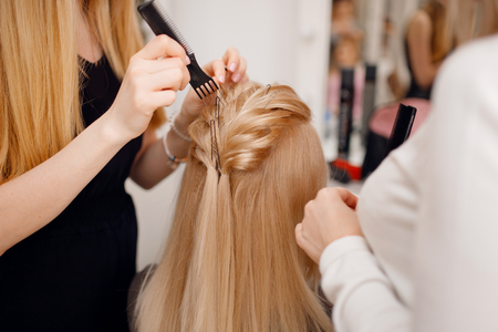 Hairdresser does hairstyle for woman to weave braids, styling. Concept wedding specialist, workshop, training.の写真素材