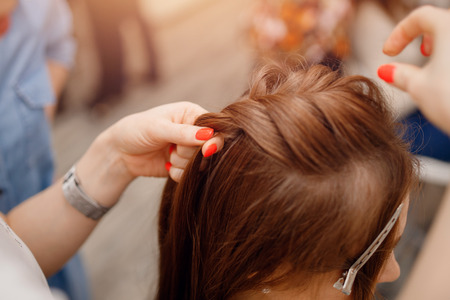 Woman hairdresser making hairstyle to blonde girl in beauty salon.の写真素材