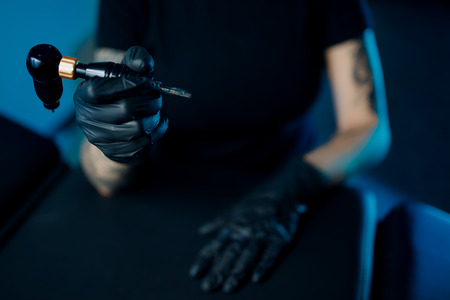 Woman master arm holding tattoo machine, preparing for drawing pictureの写真素材