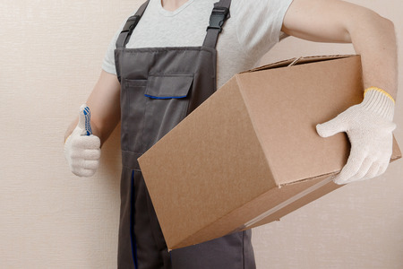 Man in to uniform of delivery suit, loader, on his head white helmet, shows gesture like, coolの写真素材