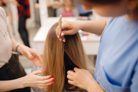 Hairdresser does hairstyle for woman to weave braids, styling. Concept wedding specialist, workshop, training.の写真素材