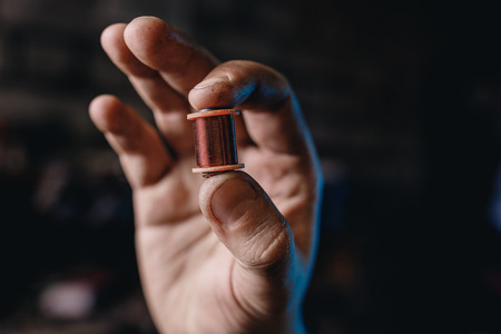 Close-up induction electric coil made of copper wire in hands of worker.の写真素材