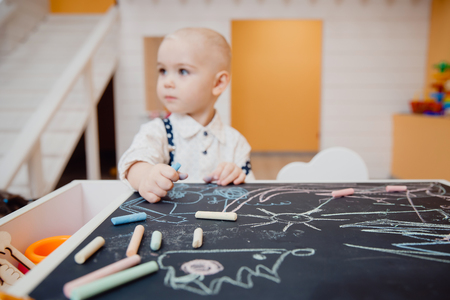 Boy child is drawn with chalk on blackboard with his hands, concept for preparing school, and developing motor skills.の写真素材