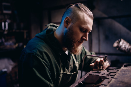 Modern worker performs work with metal, cuts out a detail, jeweler.の写真素材