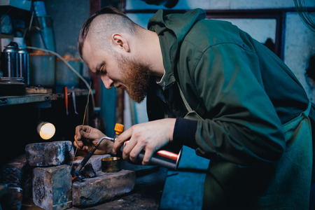 Smith jeweler produces silver metal smelting, holds gas burners in his hand.の写真素材