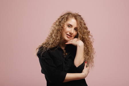 Pretty cheerful blonde head girl with curly hair smiling laughing looking at camera over pink background. copy spaceの写真素材