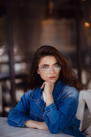 Portrait of young woman, dark hair, glasses, outdoorsの写真素材