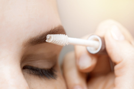 Young woman combs her eyebrows with brush in beauty salon, concept of hair correction.の写真素材