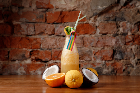 Smoothies of fresh berries yellow color. In background fresh lemons, oranges, coconut.の写真素材
