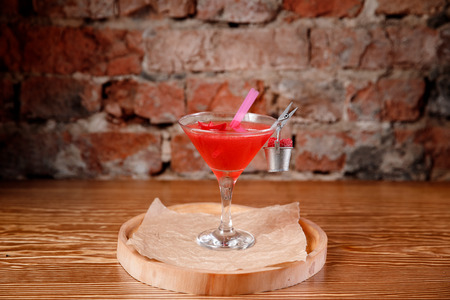 Refreshing cocktail with raspberries and alcohol, red. Martini glass is decorated clothespin and bucket.の写真素材