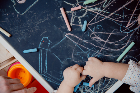 Close-up of child hand draws on chalkboard, top viewの写真素材