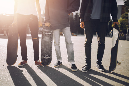 Friends of men company bully hold their hands skateboards. Concept group of street athletes studentsの写真素材