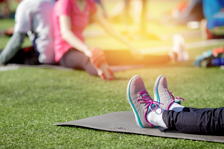 Close-up of woman on sporty rug in sportswear is practicing yoga grass lawn.の写真素材