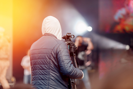 Videographer stands with his back in frame, takes recording concert on camera, an event.の写真素材
